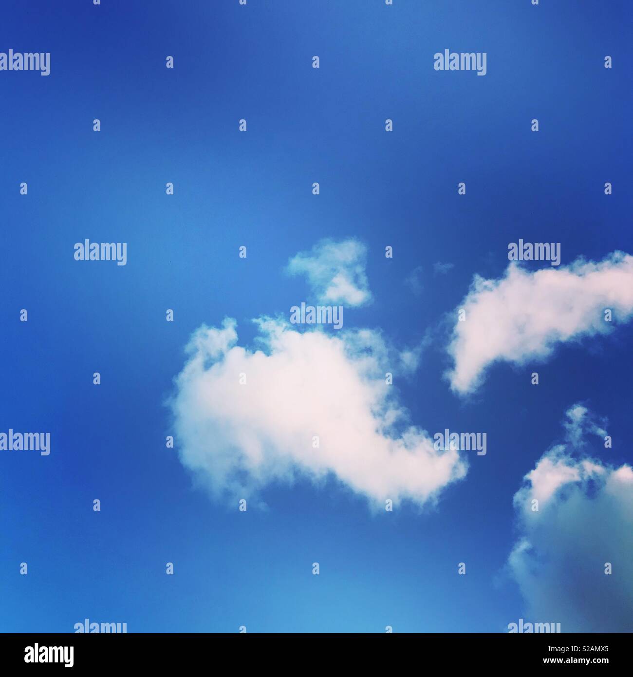 White fluffy clouds against a perfect blue sky - Smartphone Captured Stock Image