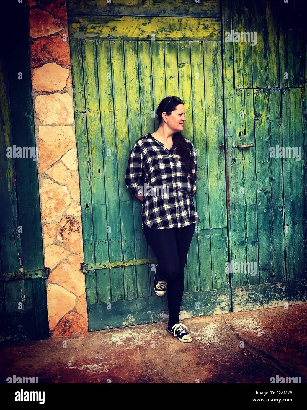 Woman posing by green boat shed doors - Smartphone Captured Stock Image