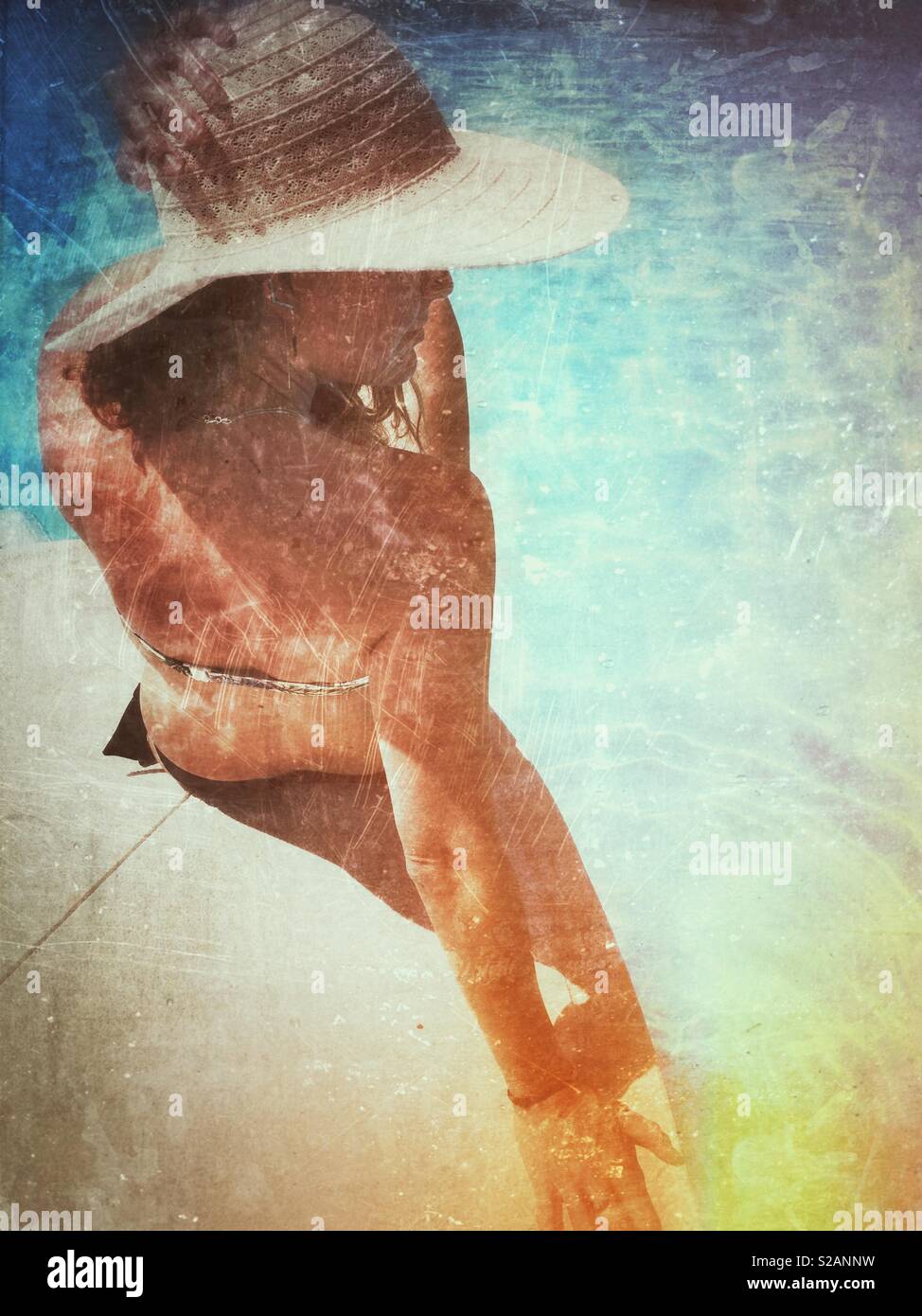 Young woman in sun hat sat on the edge of a swimming pool - Smartphone Captured Stock Image
