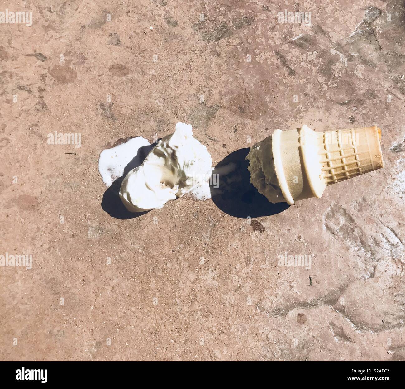 Spilt ice cream cone and ice cream melting on the cement ground on a