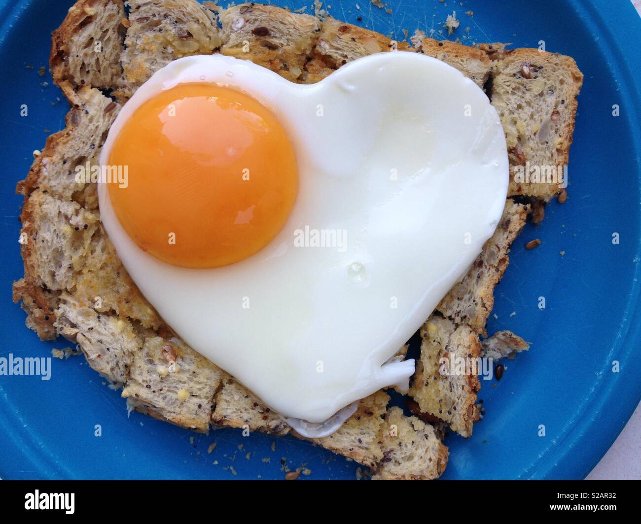 Fried egg on toast. The egg is in the shape of a healthy heart to imply a healthy diet and good well being.. Stock Photo