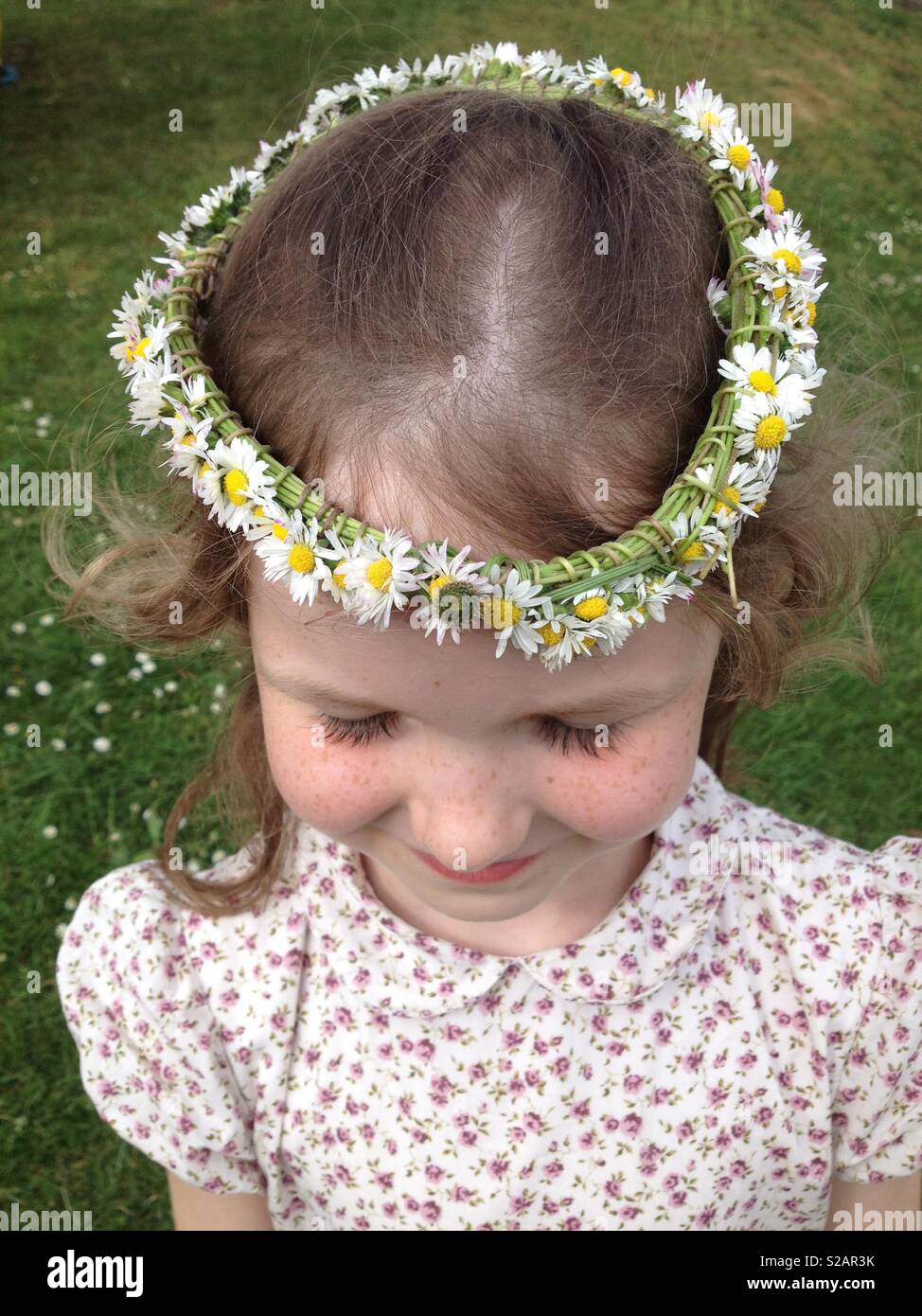 Six-year-old girl with a daisy chain on her head, in the shape of a crown. - Smartphone Captured Stock Image