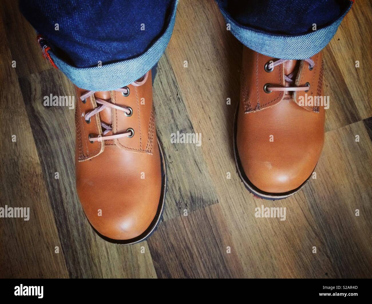 A closeup of a man wearing a pair of smart new handmade leather boots and jeans - Smartphone Captured Stock Image
