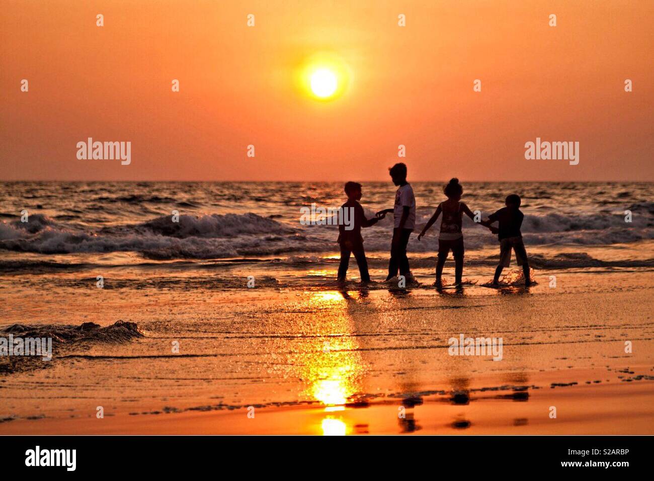 Kids playing on the beach at sunset, India - Smartphone Captured Stock Image