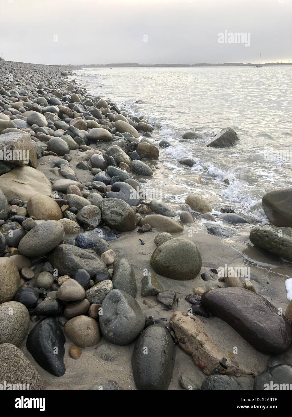 Rocks and stones line the coast of San Diego Bay in Southern California. - Smartphone Captured Stock Image