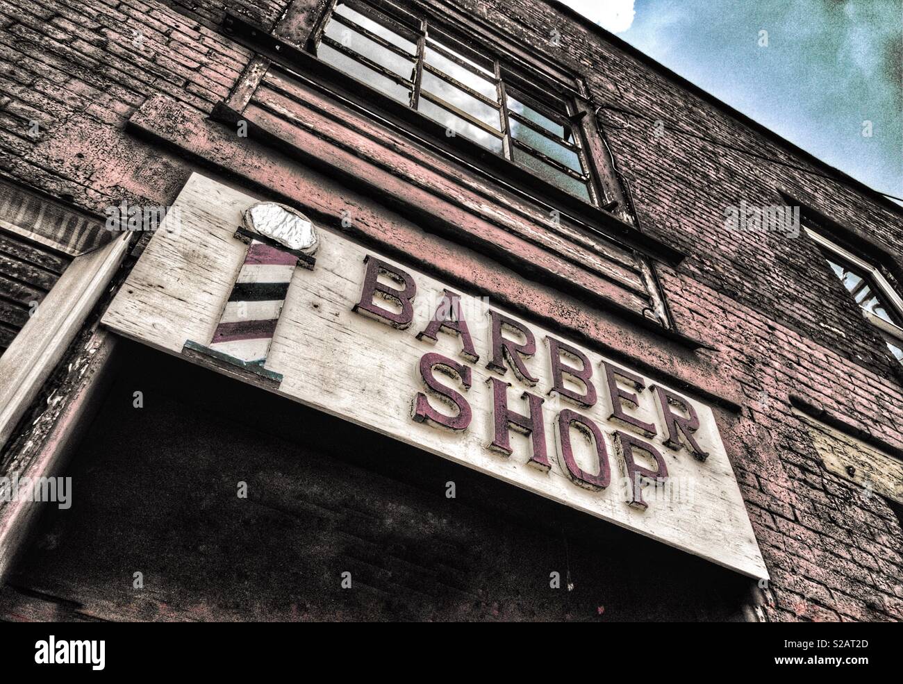 Old grungy barbershop sign on brick building Stock Photo