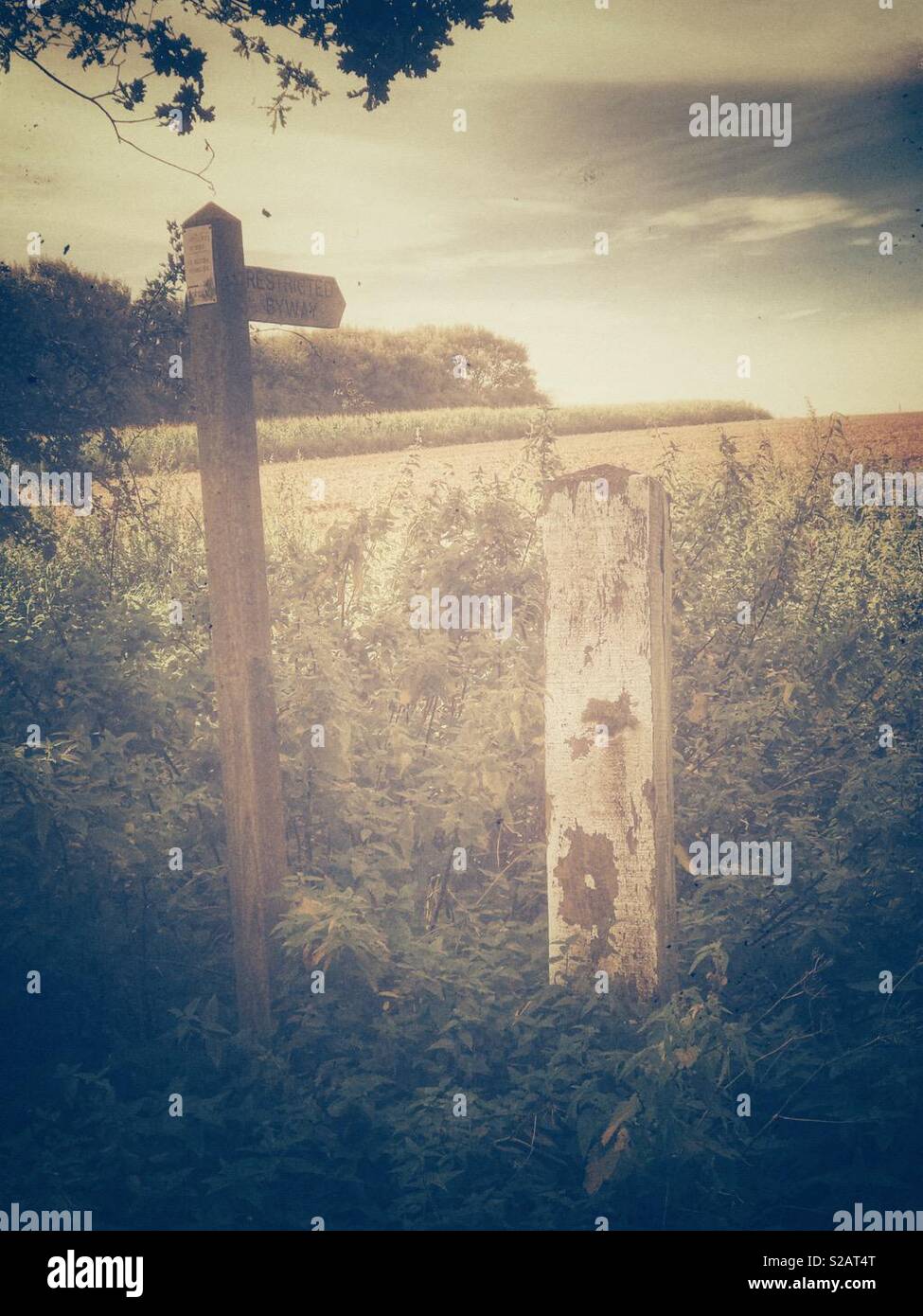 Footpath sign and old post at the edge of a ploughed field with vintage look - Smartphone Captured Stock Image