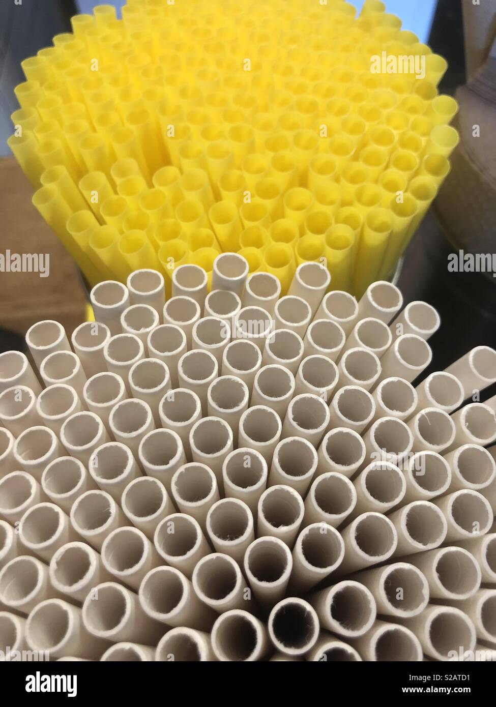 Paper and plastic straws are side by side on a restaurant counter in Southern California. Many businesses must now offer an alternative to plastic straws to meet mandatory environmental laws - Smartphone Captured Stock Image