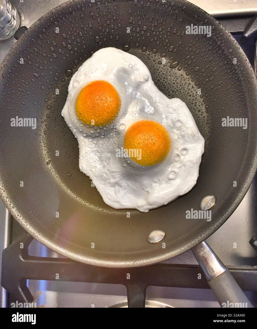 Two eggs being cooked over easy in a skillet, close up. - Smartphone Captured Stock Image