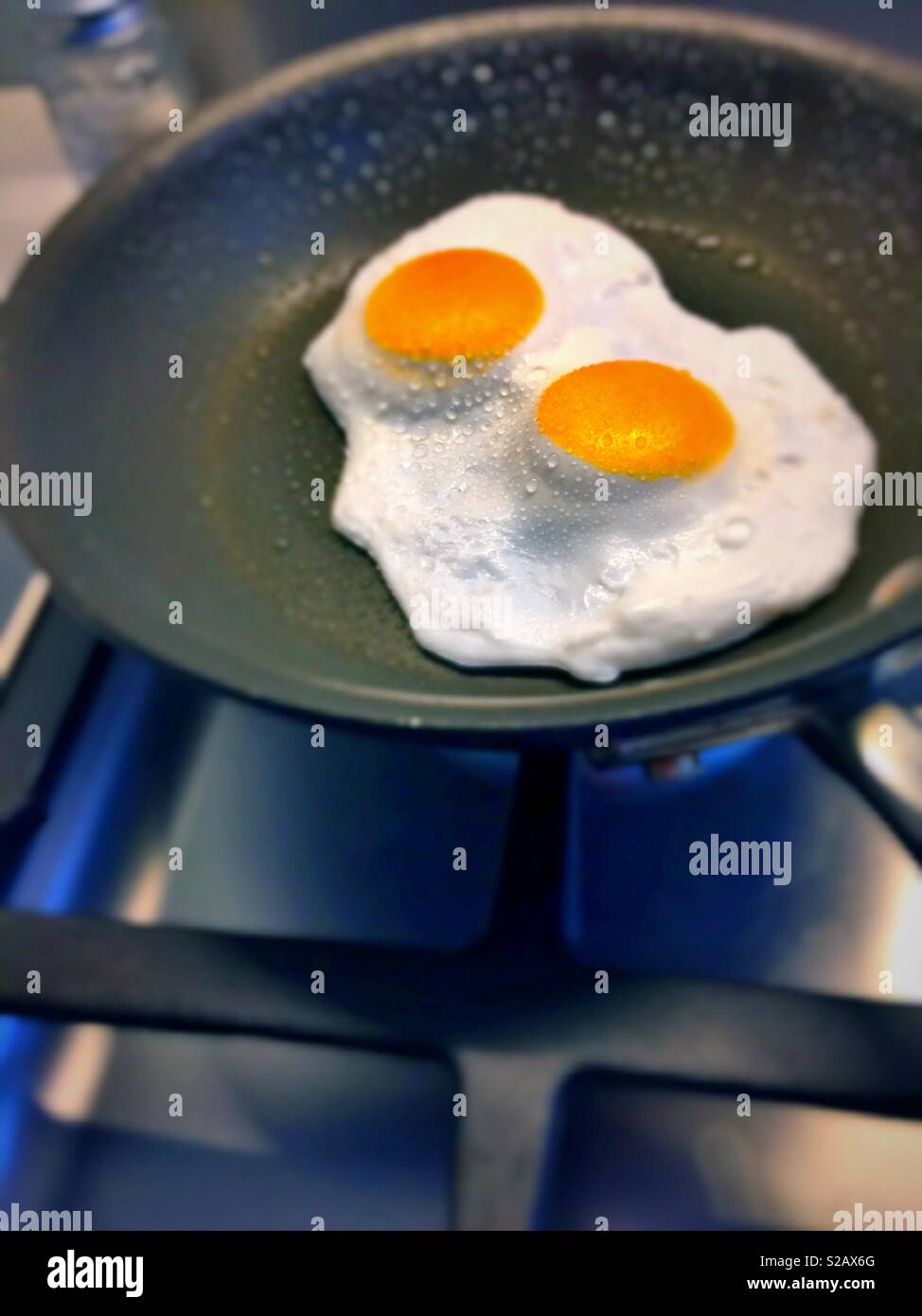 Two eggs being fried over easy in a skillet, close up - Smartphone Captured Stock Image