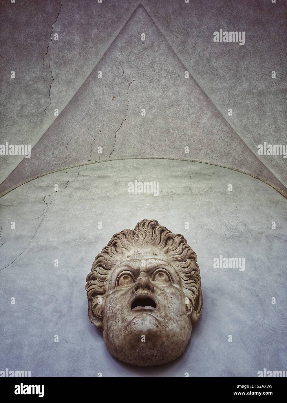 Roman sculpture above a door of a face looking up to the vaulted ceiling - Smartphone Captured Stock Image