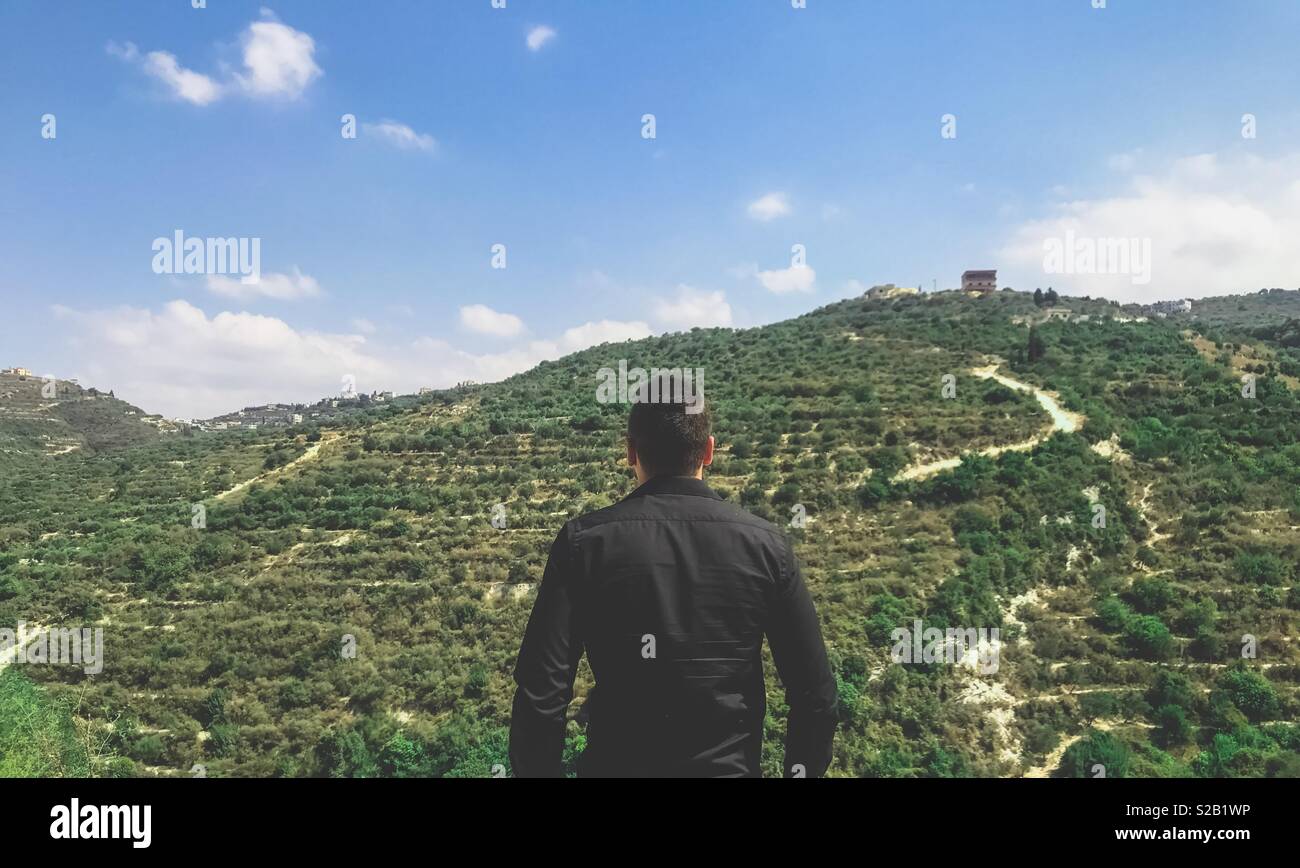 Millenial man standing in front of the beautiful green mountain in lebanon Stock Photo