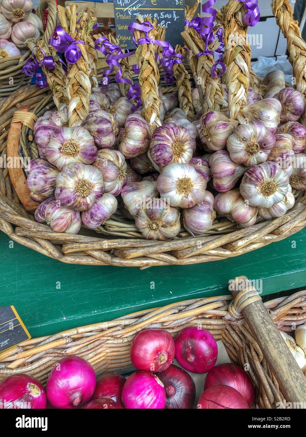 Garlic cloves and onions for sale at an outdoor market in southern France. - Smartphone Captured Stock Image