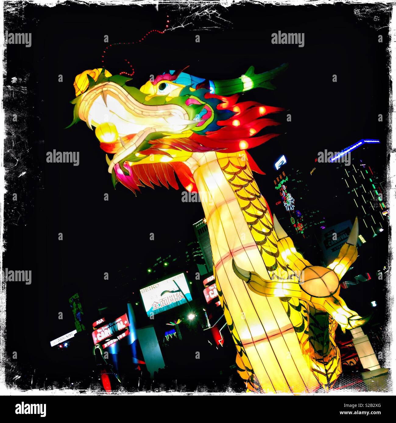 A large illuminated dragon sculpture celebrating Chinese New Year at a funfair at Hong Kong Island's Central district waterfront - Smartphone Captured Stock Image