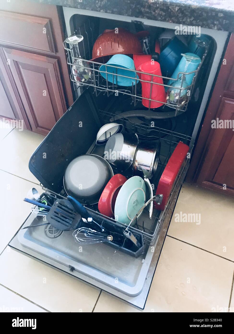 Bright color dishes loaded in the dishwasher in the kitchen Stock Photo