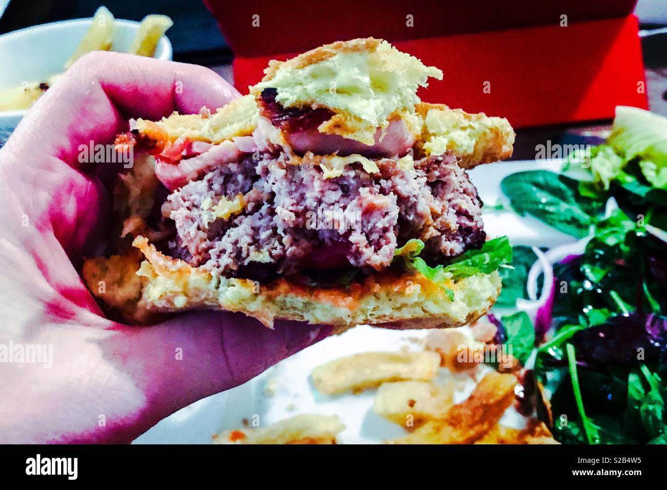 Tasty bacon and cheese burger being eaten - Smartphone Captured Stock Image