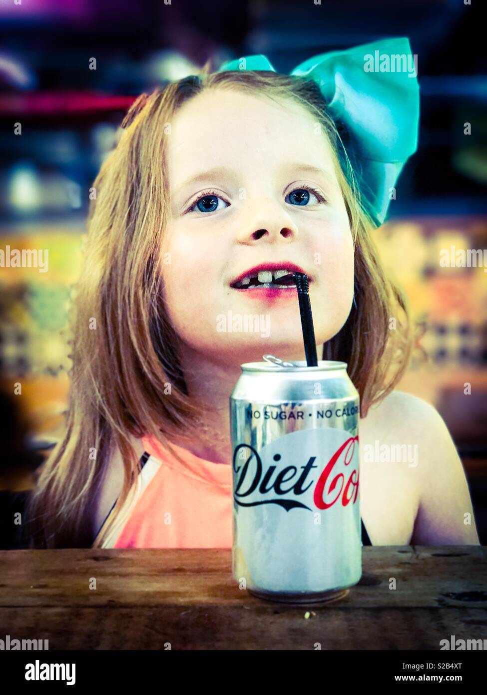 Young 7 year old girl drinking a can of Diet Cola through a straw Stock Photo