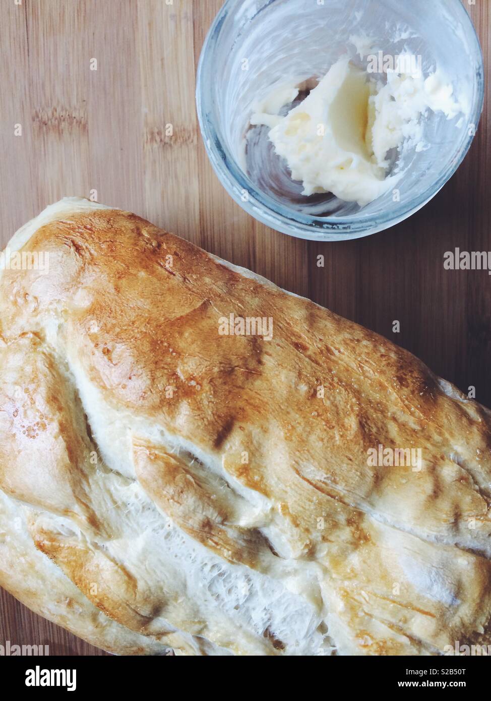 Fresh homemade baked bread loaf and freshly churned butter on a cutting board. - Smartphone Captured Stock Image