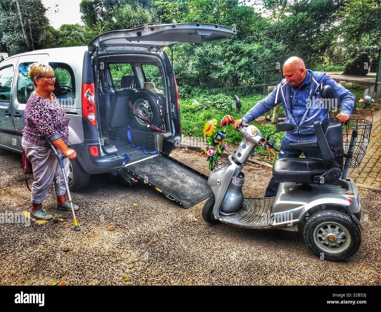 Husband getting a mobility scooter out of a car for his disabled wife to use - Smartphone Captured Stock Image
