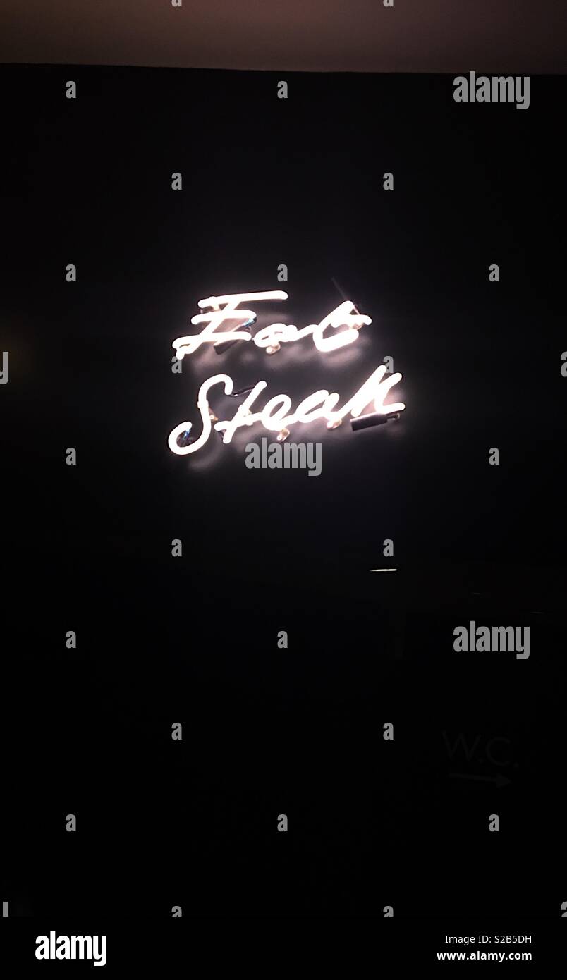 Eat steak neon white light sign at flat iron restaurant Henrietta