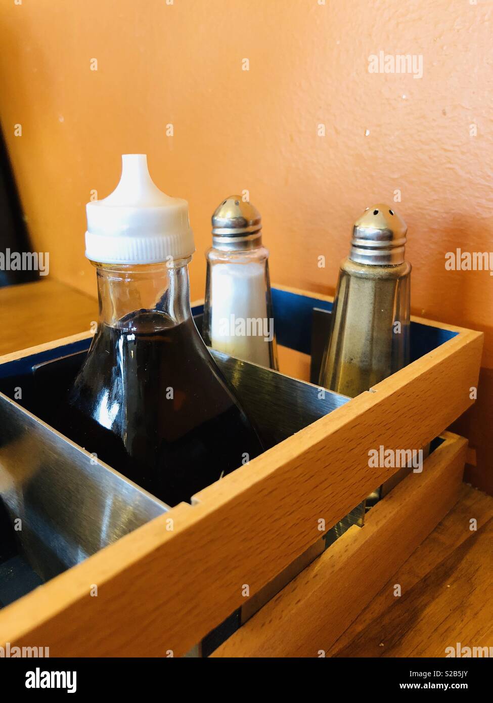 Salt, pepper and vinegar - condiments in an English café with orange painted background Stock Photo