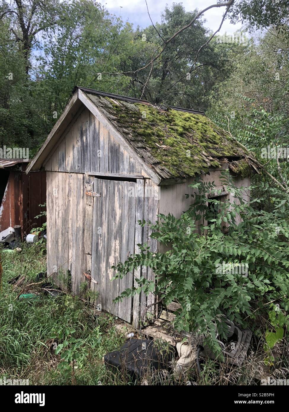 An old tool shed with moss growing on the roof on a farm in the Midwest. - Smartphone Captured Stock Image