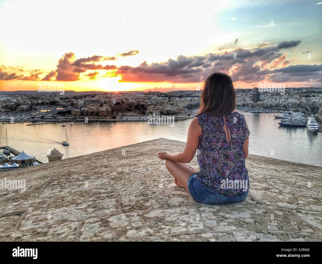 Young woman watching sunset in Valletta, Malta - Smartphone Captured Stock Image