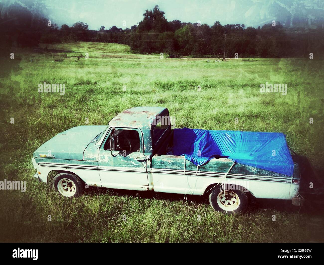 Weathered photo of vintage green and white pickup in farm field Stock Photo
