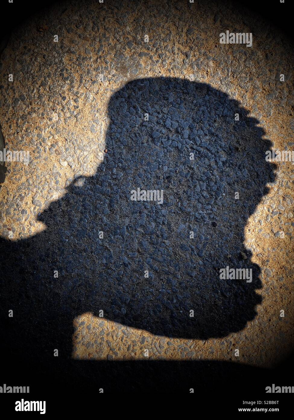 Dark shadow in strong sunshine of a foot wearing a boot Stock Photo