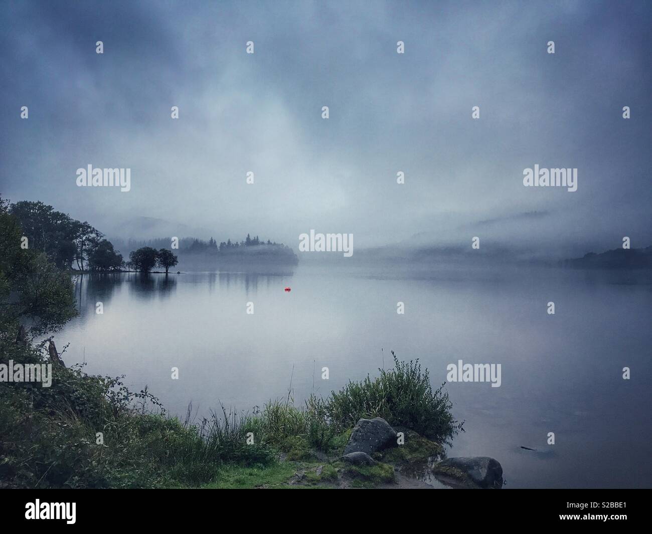 Misty morning over a loch, Loch Lomond and The Trossachs National Park, Perthshire, Scotland - Smartphone Captured Stock Image