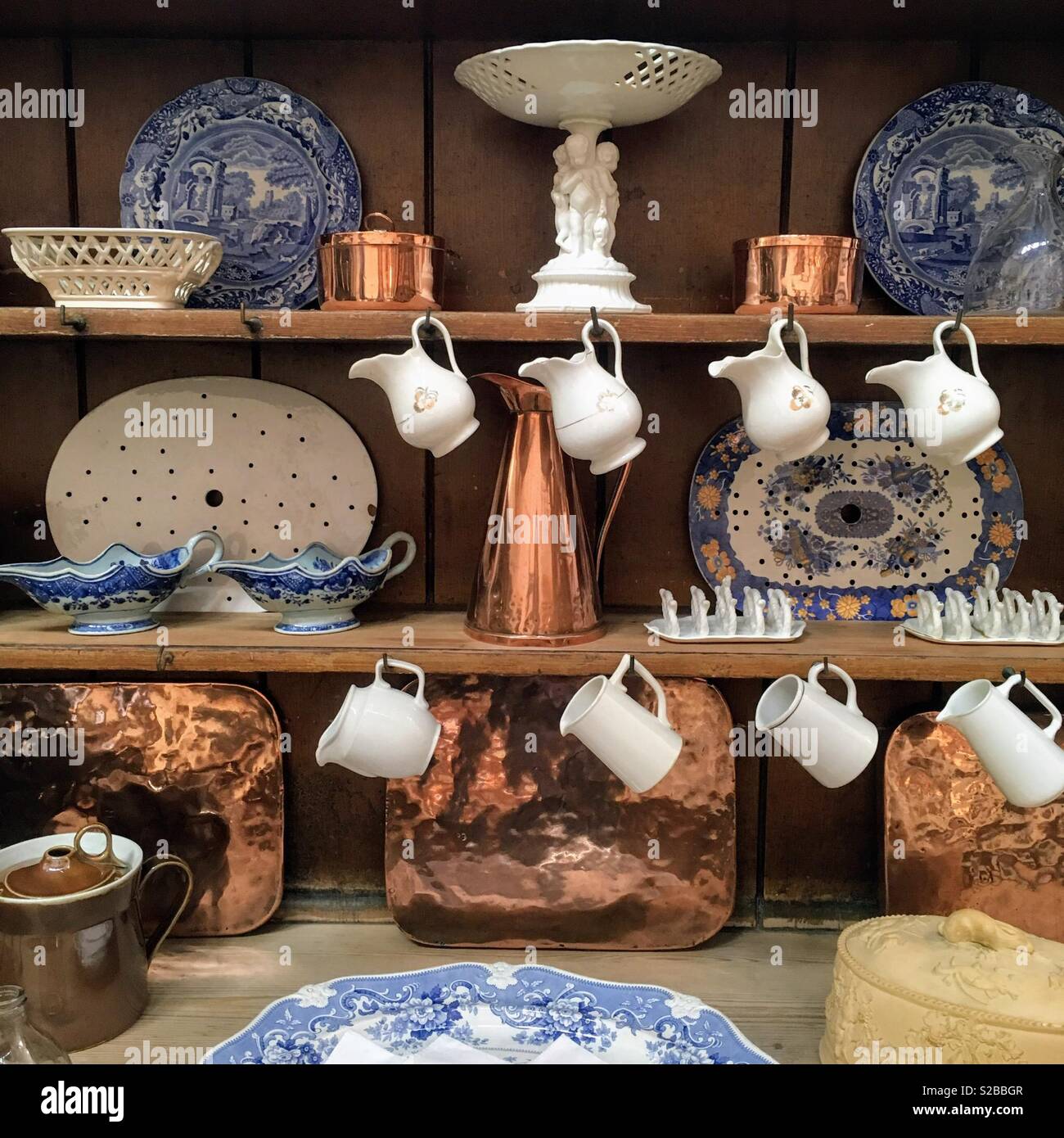 Shelves displaying items from a Victorian kitchen, including jugs, blue and white china and