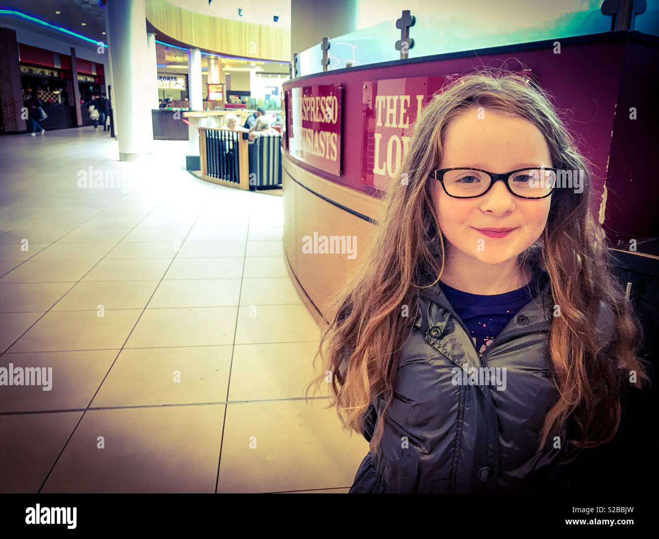 Young girl stood next to a coffee establishment in a shopping centre Stock Photo