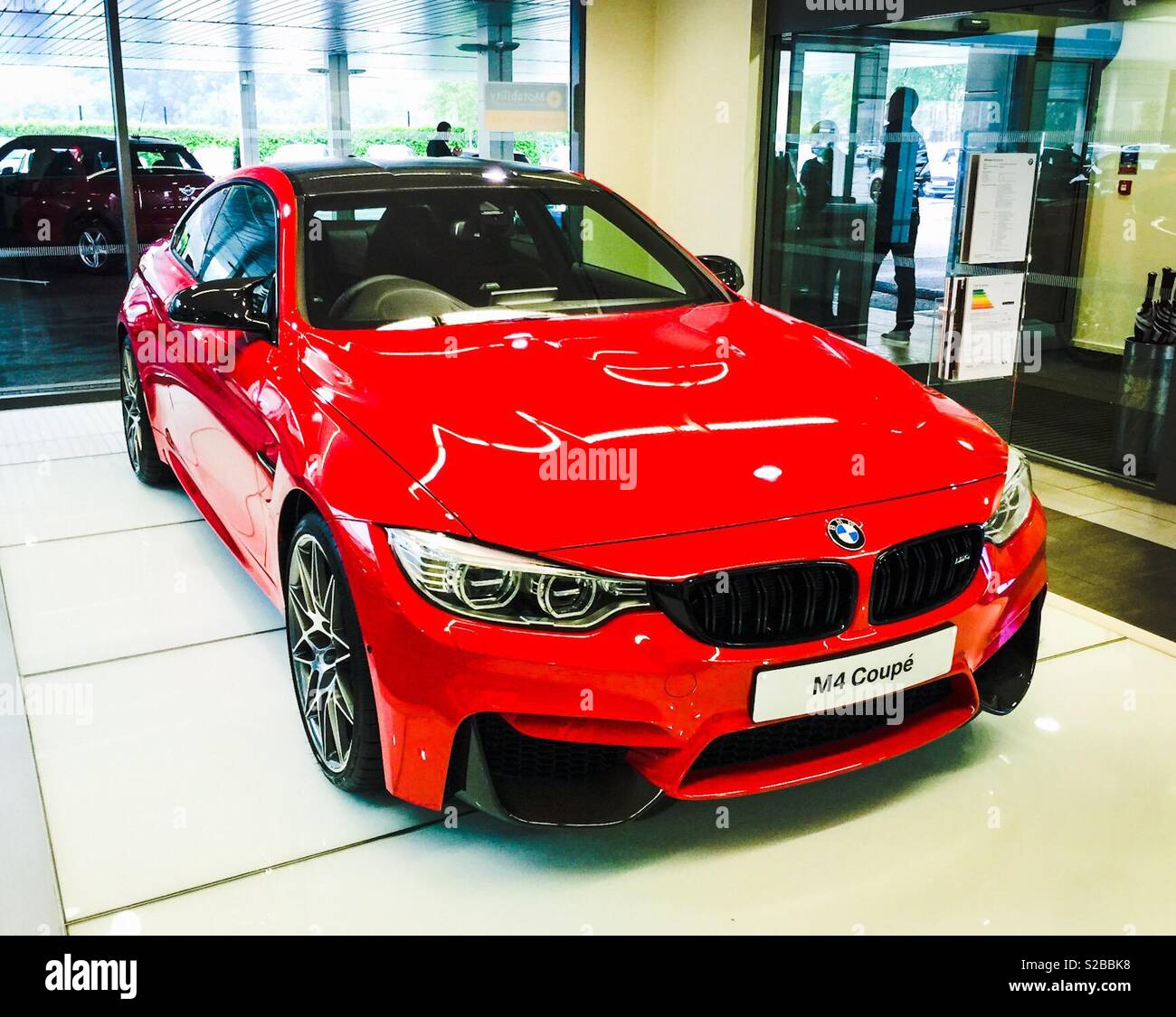 Red BMW M4 Coupe for sale in showroom Stock Photo