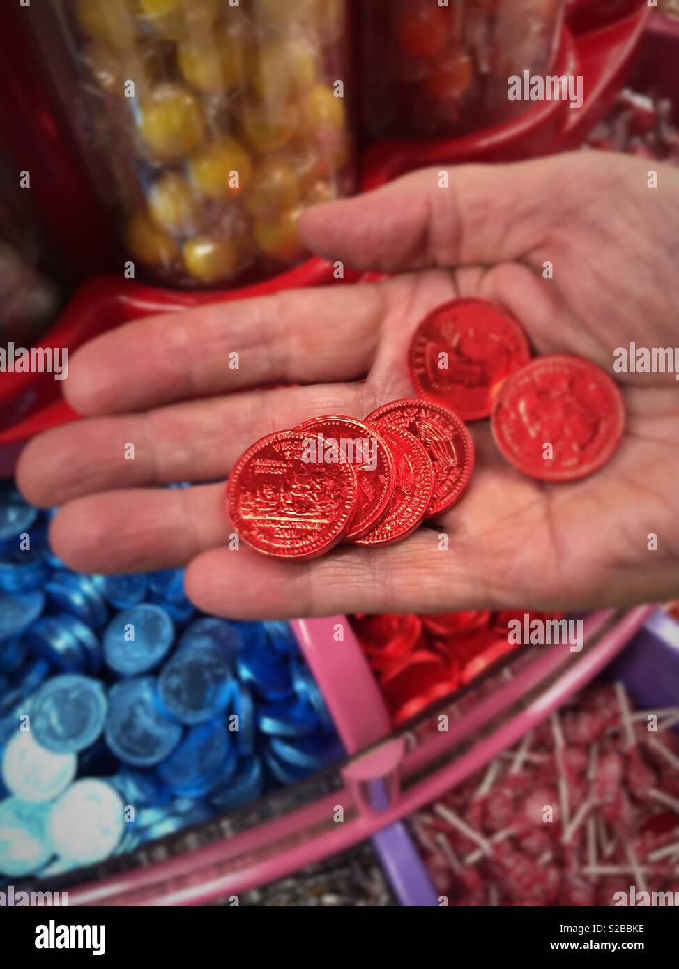 Chocolate foil covered quarters held in a man’s hand edit candy store, USA - Smartphone Captured Stock Image