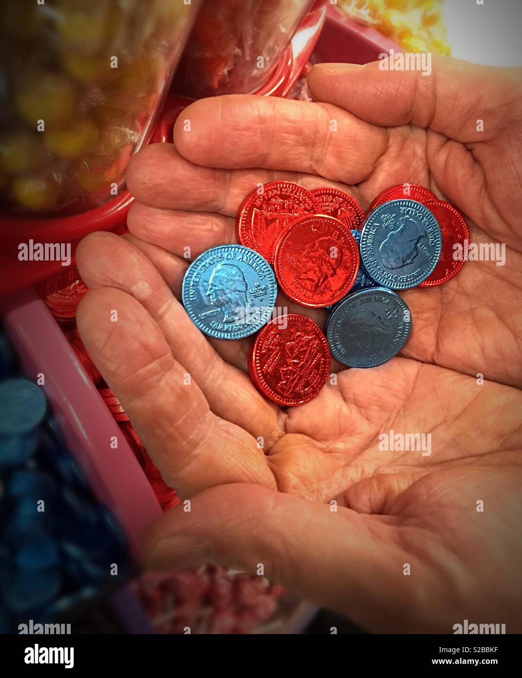 Man holding foil wrapped chocolate candy quarters, USA - Smartphone Captured Stock Image