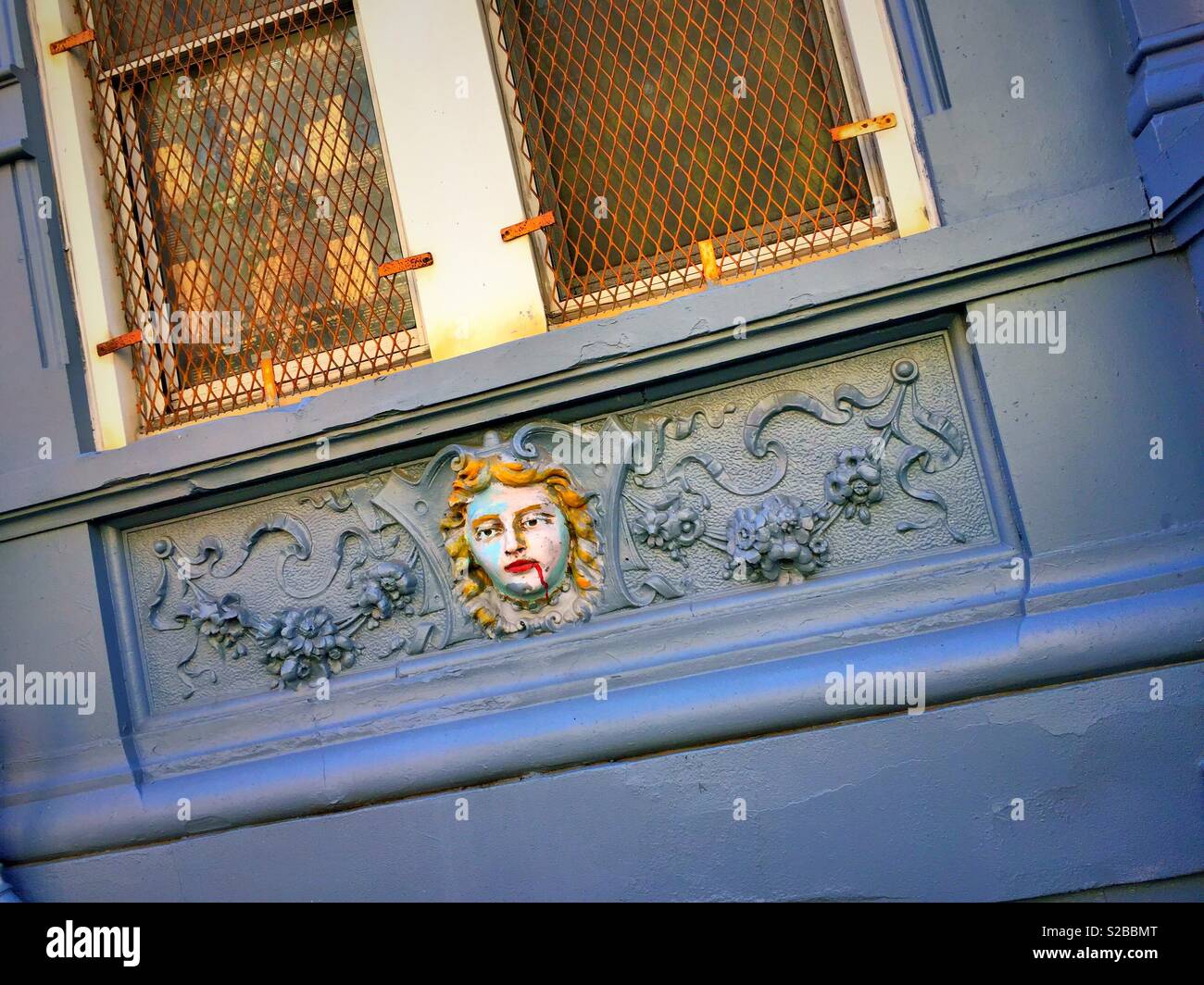 Painted relief of a face with bleeding mouth, East Village, NYC, USA - Smartphone Captured Stock Image