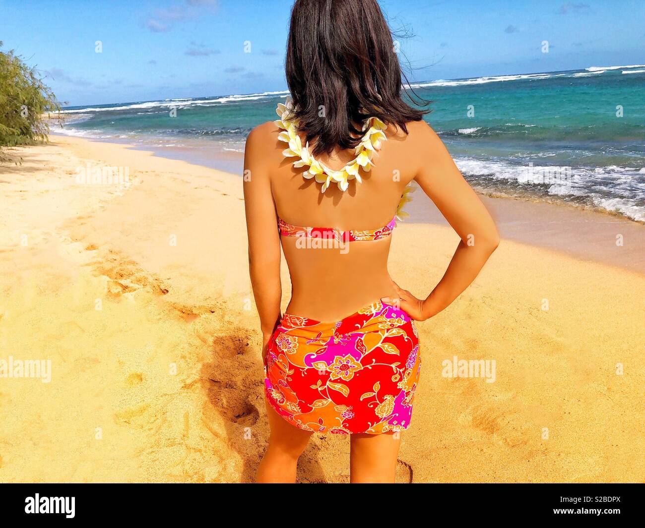 Attractive young woman on deserted tropical island beach with flower plumeria lei, brunette hair, pink bikini - Smartphone Captured Stock Image