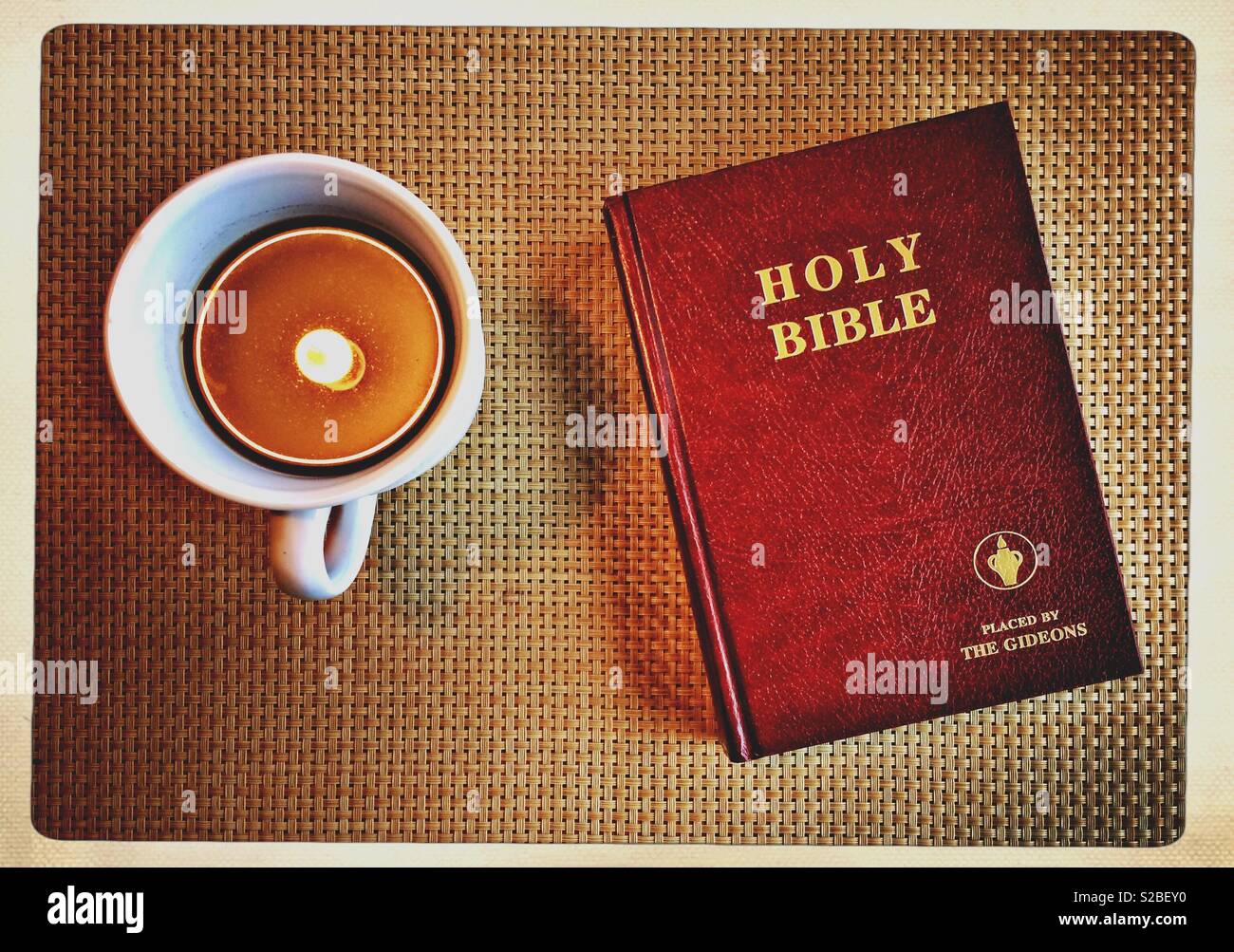 The Holy Bible by the Gideons and a cup of coffee with light reflecting in it. Top view or flat lay picture. Religion concept - Smartphone Captured Stock Image