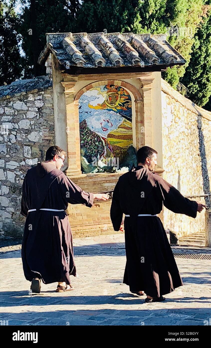 Monks at San Damiano church waving goodbye as they walk past the entrance gate Stock Photo
