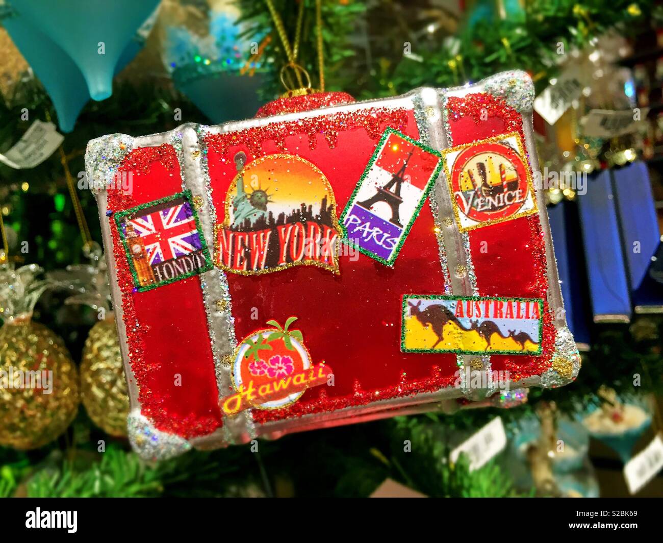 Christmas ornament in the shape of a well-traveled suitcase hanging from a Christmas tree, USA Stock Photo