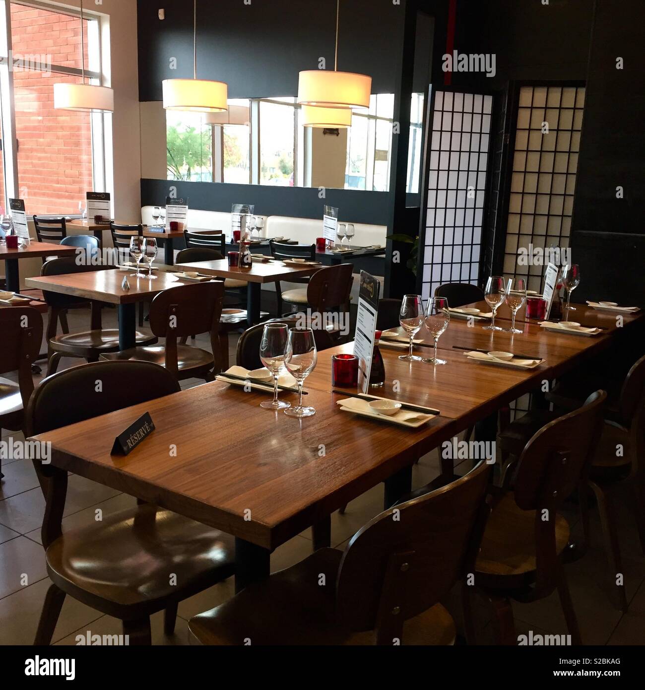 Asian restaurant - minimalist interior. No persons. Brown tables. Reserved tables. Dressed tables. Stock Photo