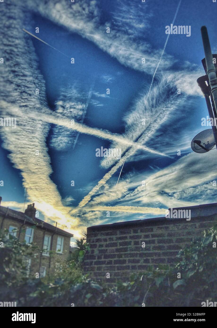 Aeroplane contrails criss-cross the skies over East Finchley, London - Smartphone Captured Stock Image