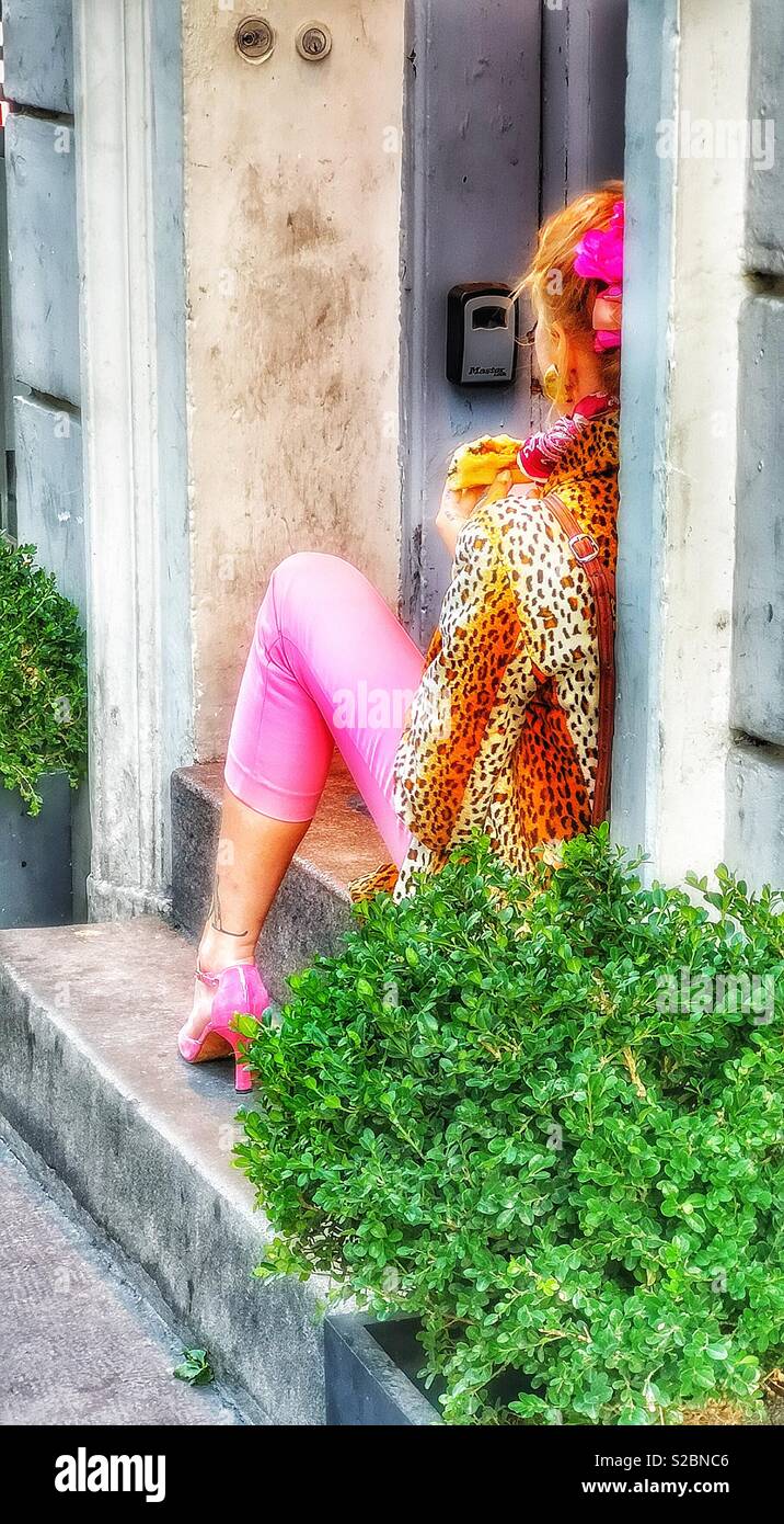 Glamorous woman eating pizza sitting in doorway Stock Photo