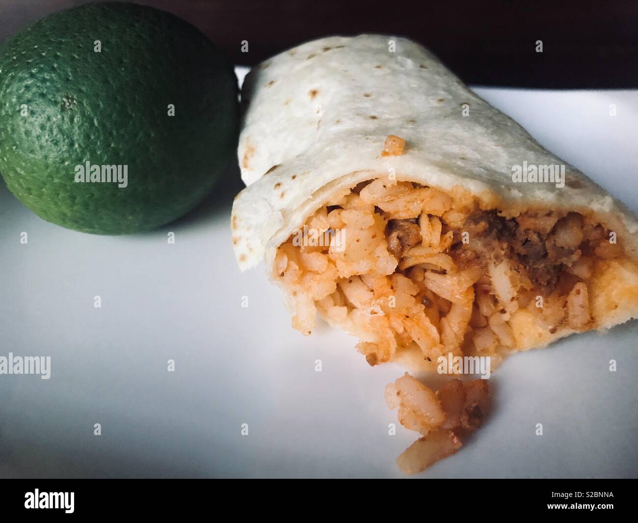 Delicious Mexican beef and rice burrito displayed on white plate with a ...