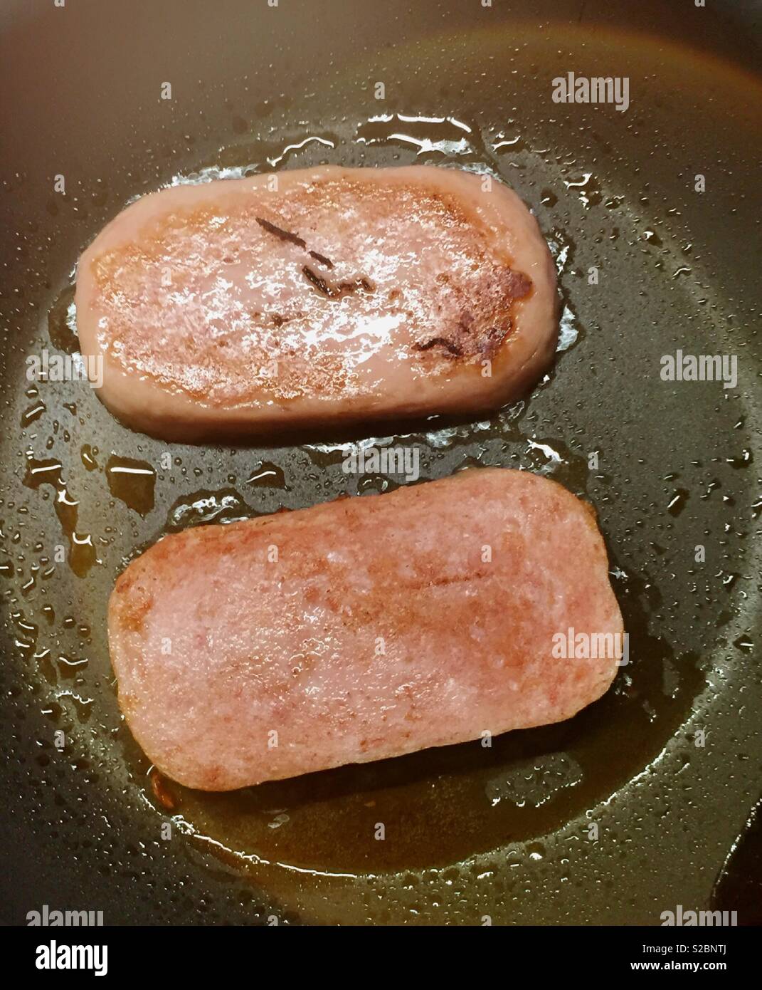 Spam slices being fried in a skillet, USA - Smartphone Captured Stock Image