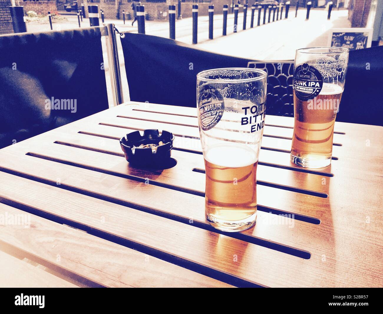 Half drunk pints of beer left on a table in a beer garden. - Smartphone Captured Stock Image