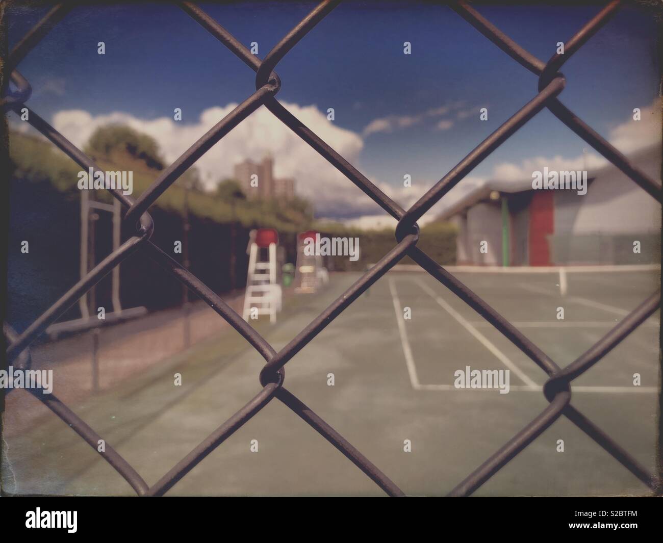 View of tennis courts through a wire mesh, on a blue sky sunny day