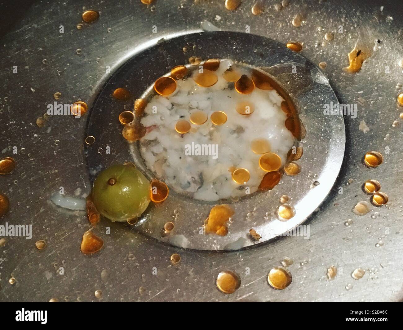 Grease and water flowing down a partially blocked sink plughole. Grease causes town and city sewers to fill with ‘Fat Bergs’ more and more each year. Stock Photo