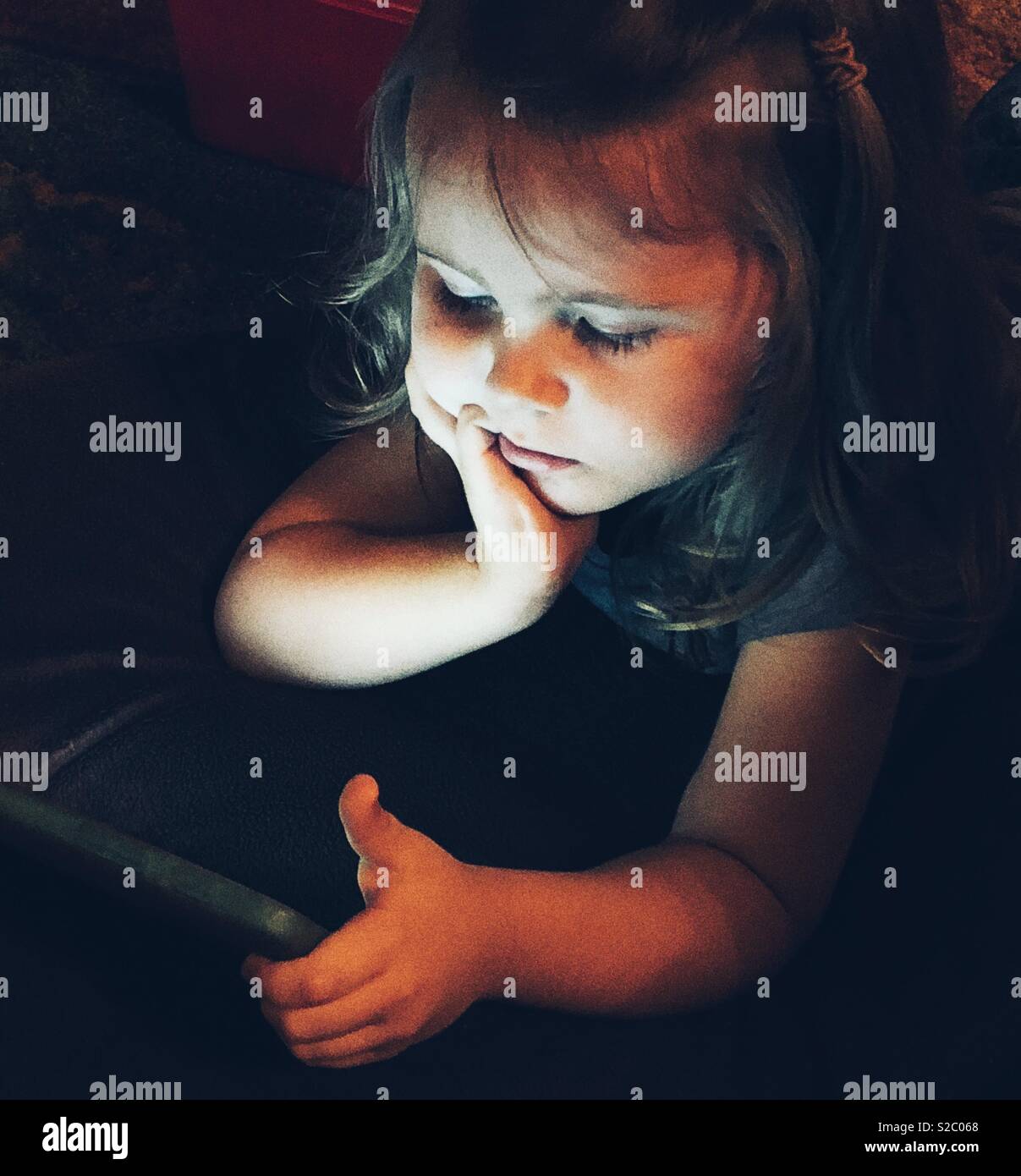 Portrait of toddler girl using a tablet in the dark - Smartphone Captured Stock Image