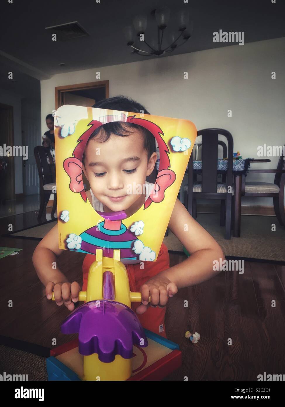 A toddler boy playing Pie Face game in a living room. - Smartphone Captured Stock Image